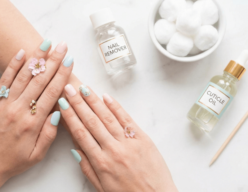 Elegant flat lay of press-on nail removal supplies on marble surface with cotton balls and cuticle oil